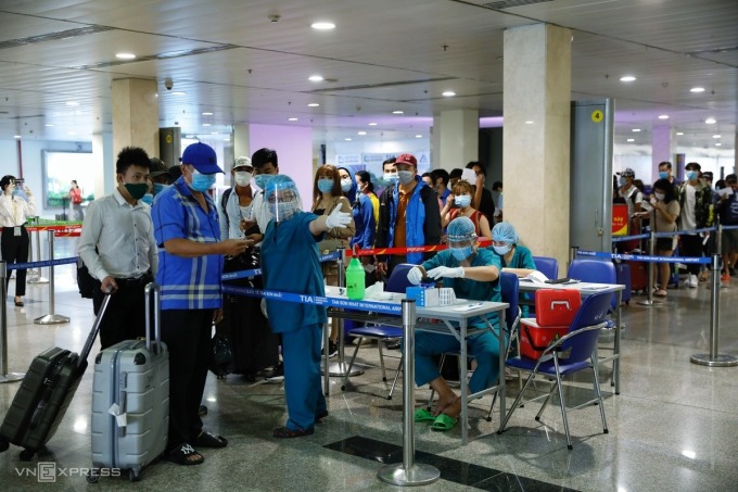 Các địa phương đón khách quốc tế Hành khách được nhân viên y tế hướng dẫn vào khu vực chờ lấy mẫu tại sân bay Tân Sơn Nhất, ngày 6/5. Ảnh: Hữu Khoa.